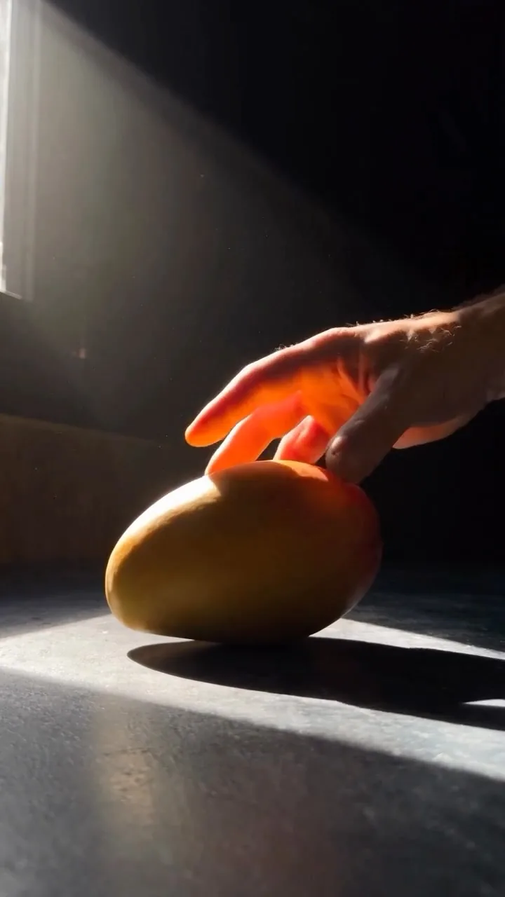 La main de l’artisan Marlotte et une mangue sur le plan de travail